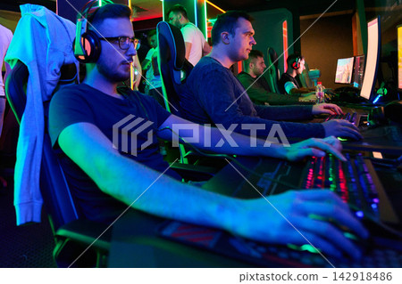 Competitive PC Gamers Playing At A Neon-Lit LAN Tournament With Headsets And RGB Keyboards Competitive PC Gamers Playing At A Neon-Lit LAN Tournament With Headsets And RGB Keyboards 142918486