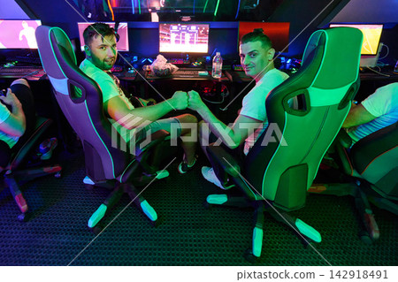Two Friends Fist Bumping While Playing Video Games In Neon Esports Gaming Room Two Friends Fist Bumping While Playing Video Games In Neon Esports Gaming Room 142918491