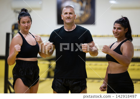 Female Boxing Athletes With Coach Posing in Gym Before Training Session Female Boxing Athletes With Coach Posing in Gym Before Training Session 142918497