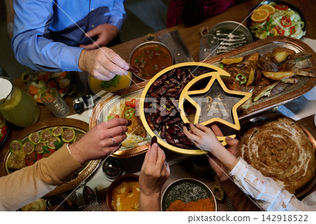 Ramadan Iftar Family Sharing Dates and Festive Food Gathering Around a Traditional Table Ramadan Iftar Family Sharing Dates and Festive Food Gathering Around a Traditional Table 142918522