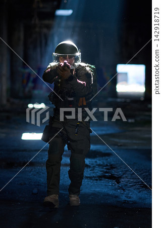 Armed Tactical Officer In Riot Gear Clearing Dark Urban Building With Rifle and Helmet Armed Tactical Officer In Riot Gear Clearing Dark Urban Building With Rifle and Helmet 142918719