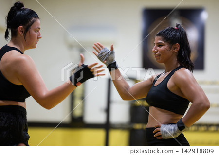 Two Female Boxers High-Five After Training Session in Gym Showing Strength, Camaraderie and Fitness Two Female Boxers High-Five After Training Session in Gym Showing Strength, Camaraderie and Fitness 142918809
