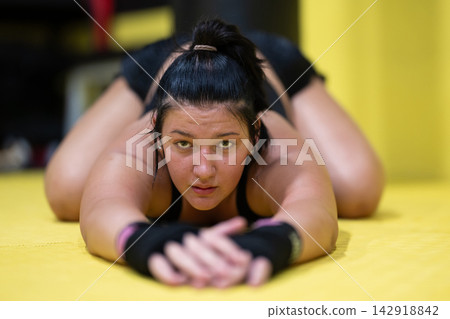 Female Athlete Stretching on Yellow Mat in Gym Preparing for MMA Training and Intense Workout Female Athlete Stretching on Yellow Mat in Gym Preparing for MMA Training and Intense Workout 142918842
