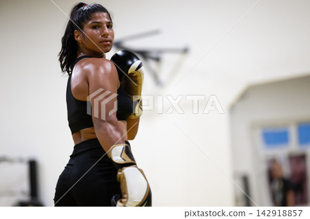 Female Boxer Athlete Training in Gym With Boxing Gloves and Intense Focus Female Boxer Athlete Training in Gym With Boxing Gloves and Intense Focus 142918857
