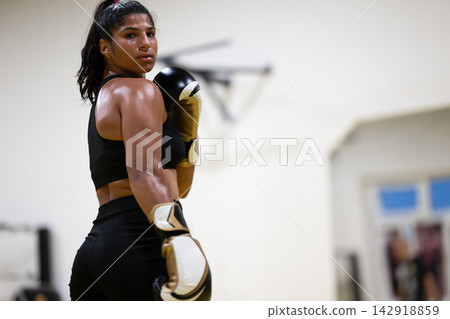 Female Boxer Training in Gym With Gloves Looking Over Shoulder After Intense Workout Session Female Boxer Training in Gym With Gloves Looking Over Shoulder After Intense Workout Session 142918859