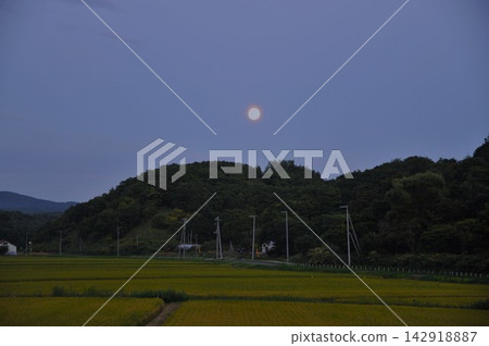 黃昏時分,月亮升起在鄉村之上:北海道寧靜的鄉村景色。 黃昏時分,月亮升起在鄉村之上:北海道寧靜的鄉村景色。 142918887