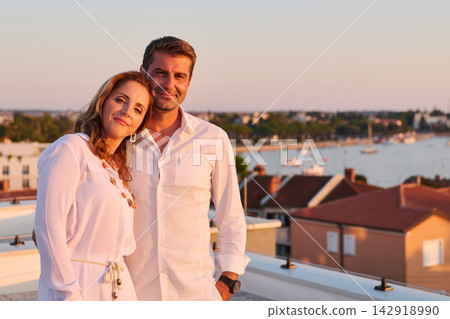 Mature Couple Relaxing on Rooftop Balcony With Sea View at Sunset in Coastal Town Mature Couple Relaxing on Rooftop Balcony With Sea View at Sunset in Coastal Town 142918990