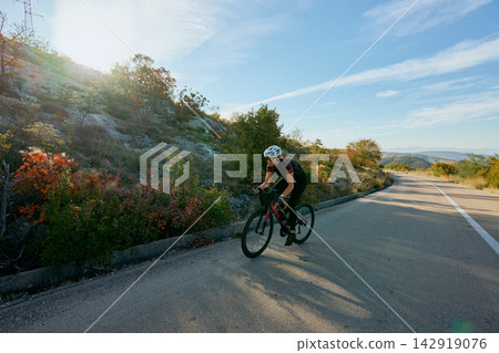 Female Cyclist Training on Scenic Road Through Hills at Sunrise Outdoor Cycling and Fitness Lifestyle Female Cyclist Training on Scenic Road Through Hills at Sunrise Outdoor Cycling and Fitness Lifestyle 142919076
