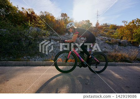 Female Cyclist Training On Road Bike During Autumn Ride Through Rocky Countryside 142919086