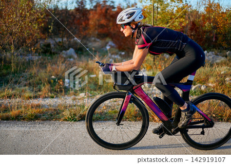 Female Cyclist Training On Road Bike Outdoors In Autumn Landscape Speed, Endurance And Fitness Female Cyclist Training On Road Bike Outdoors In Autumn Landscape Speed, Endurance And Fitness 142919107
