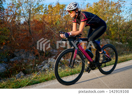 Female Cyclist Training on Road Bike in Autumn Landscape Fitness Cycling and Triathlon Preparation Female Cyclist Training on Road Bike in Autumn Landscape Fitness Cycling and Triathlon Preparation 142919108