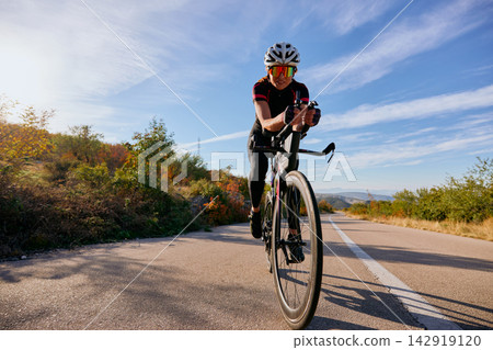 Female Cyclist Training On Road Bike During Sunny Outdoor Ride Through Scenic Countryside Female Cyclist Training On Road Bike During Sunny Outdoor Ride Through Scenic Countryside 142919120
