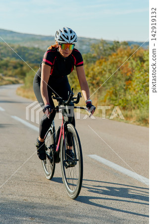 Female Cyclist Training on Open Road With Helmet and Sunglasses - Outdoor Road Cycling Fitness Female Cyclist Training on Open Road With Helmet and Sunglasses - Outdoor Road Cycling Fitness 142919132