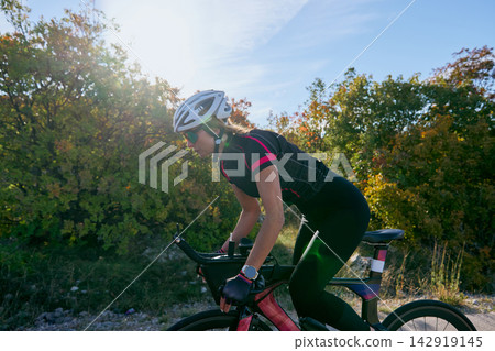 Female Cyclist Training On Road Bike During Sunny Autumn Ride With Helmet And Sunglasses Female Cyclist Training On Road Bike During Sunny Autumn Ride With Helmet And Sunglasses 142919145