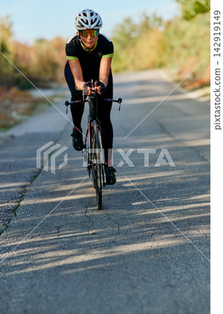 Female Cyclist Training on a Road Bike Wearing Helmet and Sunglasses for Speed and Fitness Female Cyclist Training on a Road Bike Wearing Helmet and Sunglasses for Speed and Fitness 142919149