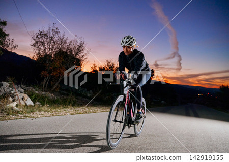 Female Cyclist Training on Rural Road at Sunset Twilight Road Bike Fitness and Endurance Female Cyclist Training on Rural Road at Sunset Twilight Road Bike Fitness and Endurance 142919155