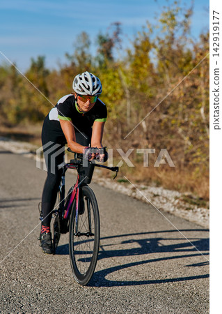 Female Cyclist Training On Road Bike Outdoors Wearing Helmet And Sunglasses During Sunny Ride 142919177