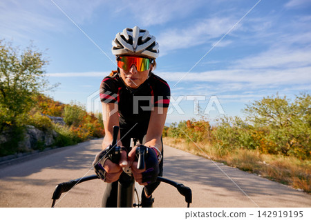 Female Cyclist Training On Road Bike Wearing Helmet And Sunglasses During Sunny Outdoor Ride Female Cyclist Training On Road Bike Wearing Helmet And Sunglasses During Sunny Outdoor Ride 142919195