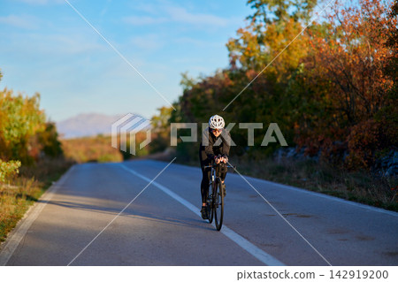 Solo Cyclist Riding Road Bike Through Autumn Landscape On Empty Country Road For Fitness Training Solo Cyclist Riding Road Bike Through Autumn Landscape On Empty Country Road For Fitness Training 142919200