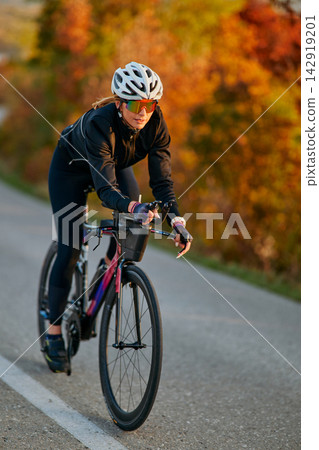 Female Cyclist Training on Road Bike During Autumn Golden Hour Ride Female Cyclist Training on Road Bike During Autumn Golden Hour Ride 142919201