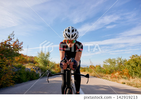 Road Cyclist Training on Time Trial Bike With Helmet and Sunglasses on Scenic Autumn Route Road Cyclist Training on Time Trial Bike With Helmet and Sunglasses on Scenic Autumn Route 142919213