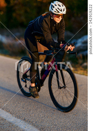 Female Cyclist On Road Bike Training At Sunset Wearing Helmet And Sport Sunglasses Female Cyclist On Road Bike Training At Sunset Wearing Helmet And Sport Sunglasses 142919222