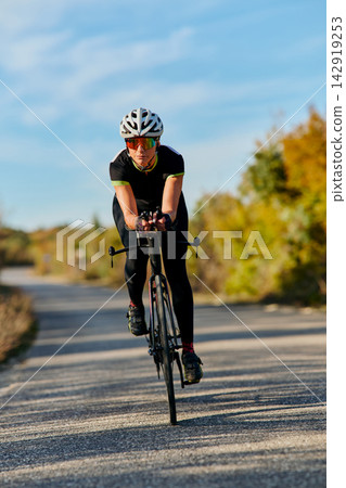 Female Cyclist Training on Road Bike Outdoors During Sunny Fall Ride for Fitness and Speed Female Cyclist Training on Road Bike Outdoors During Sunny Fall Ride for Fitness and Speed 142919253