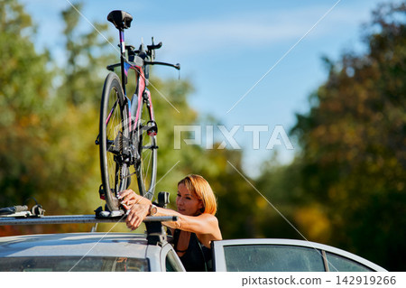 Woman Mounting Road Bike On Car Roof Rack Before Outdoor Cycling Trip Woman Mounting Road Bike On Car Roof Rack Before Outdoor Cycling Trip 142919266