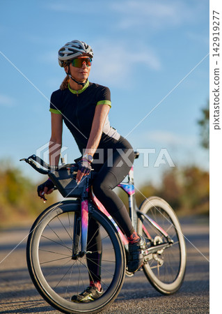 Female Cyclist On Road Bike Wearing Helmet And Sunglasses During Outdoor Training Ride Female Cyclist On Road Bike Wearing Helmet And Sunglasses During Outdoor Training Ride 142919277