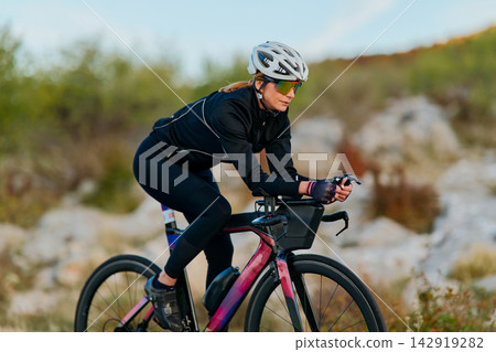 Female Cyclist Riding Road Bike On Scenic Outdoor Training Ride Wearing Helmet And Sunglasses Female Cyclist Riding Road Bike On Scenic Outdoor Training Ride Wearing Helmet And Sunglasses 142919282