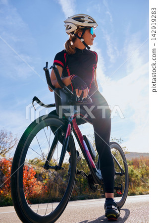 Female Cyclist Training On Road Bike With Helmet And Sunglasses During Sunny Outdoor Ride Female Cyclist Training On Road Bike With Helmet And Sunglasses During Sunny Outdoor Ride 142919283