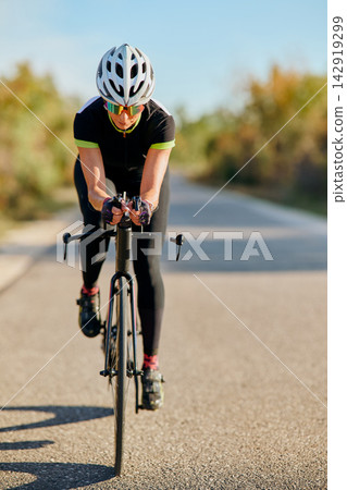 Female Cyclist Riding Road Bike in Aerodynamic Position Training on Sunny Country Road Female Cyclist Riding Road Bike in Aerodynamic Position Training on Sunny Country Road 142919299