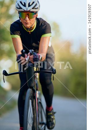 Female Cyclist On Road Bike Training Outdoors Wearing Helmet And Reflective Sunglasses Female Cyclist On Road Bike Training Outdoors Wearing Helmet And Reflective Sunglasses 142919307