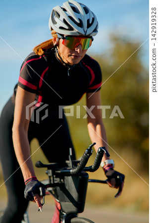 Female Cyclist Training on Triathlon Bike With Helmet and Sunglasses in Outdoor Road Workout Female Cyclist Training on Triathlon Bike With Helmet and Sunglasses in Outdoor Road Workout 142919328