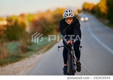 Road Cyclist Training On Scenic Country Road At Dawn Wearing Helmet And Cycling Gear Road Cyclist Training On Scenic Country Road At Dawn Wearing Helmet And Cycling Gear 142919344