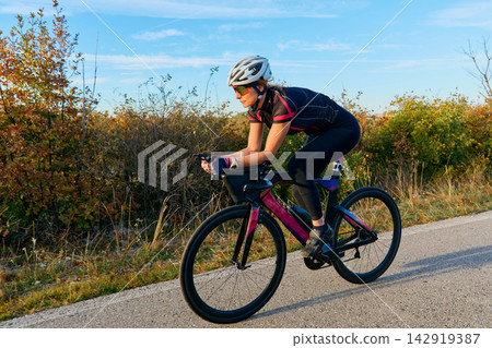 Female Cyclist Training On Aerodynamic Road Bike During Autumn Morning Countryside Ride Female Cyclist Training On Aerodynamic Road Bike During Autumn Morning Countryside Ride 142919387