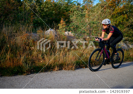 Female Cyclist Riding A Road Bike On Countryside Path During Autumn Training Ride Female Cyclist Riding A Road Bike On Countryside Path During Autumn Training Ride 142919397