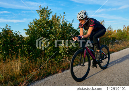Female Cyclist Riding Road Bike Outdoors on Sunny Day Training for Triathlon or Fitness Female Cyclist Riding Road Bike Outdoors on Sunny Day Training for Triathlon or Fitness 142919401