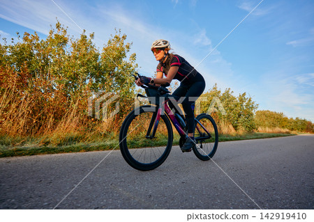 Female Cyclist Training On Road Bike Along Country Road At Sunrise Female Cyclist Training On Road Bike Along Country Road At Sunrise 142919410