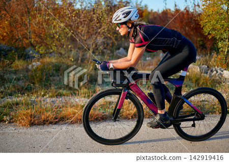 Female Cyclist Training on Aerodynamic Road Bike During Outdoor Fitness Ride at Sunrise Female Cyclist Training on Aerodynamic Road Bike During Outdoor Fitness Ride at Sunrise 142919416
