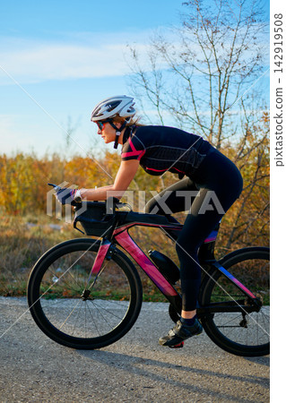Female Cyclist Riding Aero Road Bike In Time-Trial Position Through Autumn Landscape Female Cyclist Riding Aero Road Bike In Time-Trial Position Through Autumn Landscape 142919508