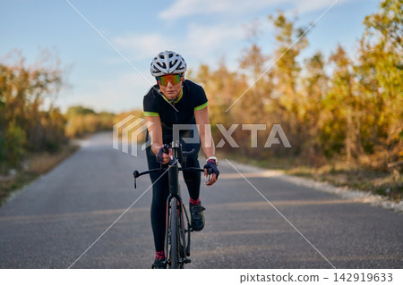 Female Cyclist Training On Rural Road With Helmet And Sunglasses During Autumn Outdoor Ride Female Cyclist Training On Rural Road With Helmet And Sunglasses During Autumn Outdoor Ride 142919633