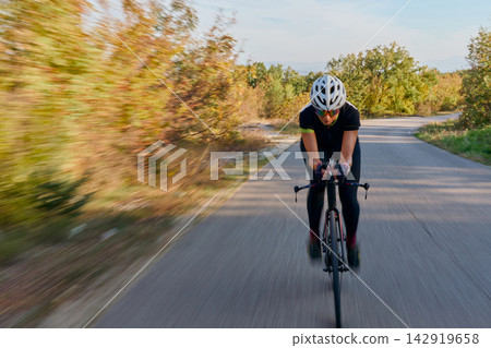 Road Cyclist Training at Speed on a Scenic Country Route Wearing Helmet and Aerodynamic Gear Road Cyclist Training at Speed on a Scenic Country Route Wearing Helmet and Aerodynamic Gear 142919658