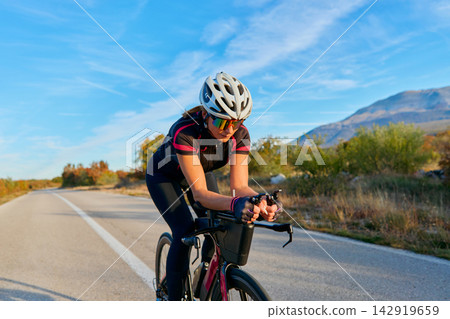 Female Cyclist Training On Road Bike In Scenic Countryside During Sunny Outdoor Ride 142919659