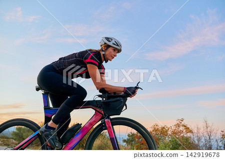 Female Cyclist Training On Aero Road Bike At Sunset Outdoor Fitness Ride For Endurance Female Cyclist Training On Aero Road Bike At Sunset Outdoor Fitness Ride For Endurance 142919678