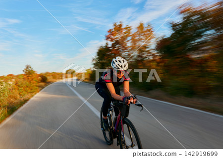 Female Cyclist Training on Rural Road at High Speed in Autumn With Helmet and Sunglasses Female Cyclist Training on Rural Road at High Speed in Autumn With Helmet and Sunglasses 142919699