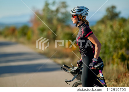 Female Cyclist On Road Bike Training Outdoors: Woman Cycling for Fitness and Endurance Female Cyclist On Road Bike Training Outdoors: Woman Cycling for Fitness and Endurance 142919703