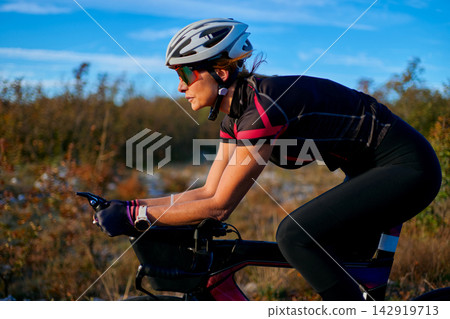 Female Cyclist Training in Aerodynamic Position on Road Bike During Outdoor Triathlon Workout Female Cyclist Training in Aerodynamic Position on Road Bike During Outdoor Triathlon Workout 142919713