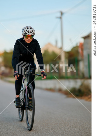 Female Cyclist Riding Road Bike Outdoors Wearing Helmet And Sunglasses During Training Female Cyclist Riding Road Bike Outdoors Wearing Helmet And Sunglasses During Training 142919732