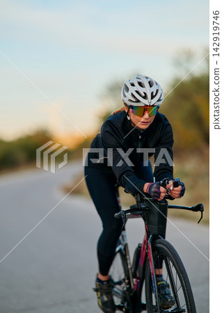 Female Cyclist Riding Road Bike Outdoors at Sunrise Training for Fitness and Endurance Female Cyclist Riding Road Bike Outdoors at Sunrise Training for Fitness and Endurance 142919746